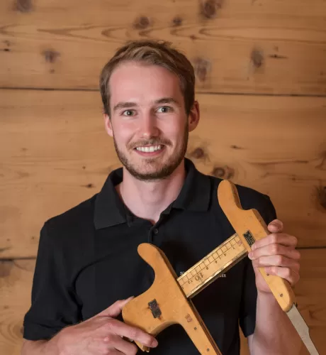 Jan Bucher mit einem alten Werkzeug in der Hand und ein schwarzer Schreinerei Eichenberger Polo Shirt